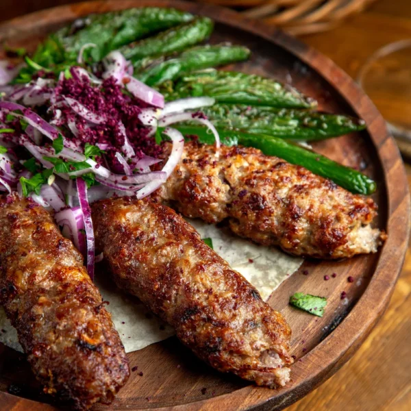 side-view-lula-kebab-with-red-onions-sumakh-grilled-green-chili-peppers-wooden-board (1)