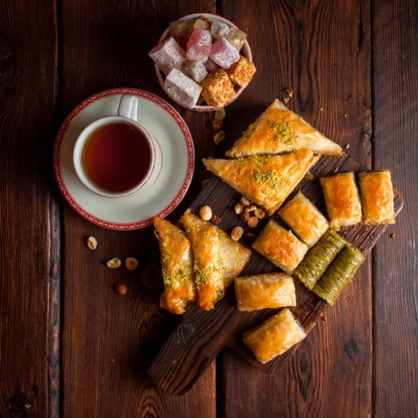 top-view-assorted-turkish-baklava-with-cup-tea-turkish-delight-wooden-plank