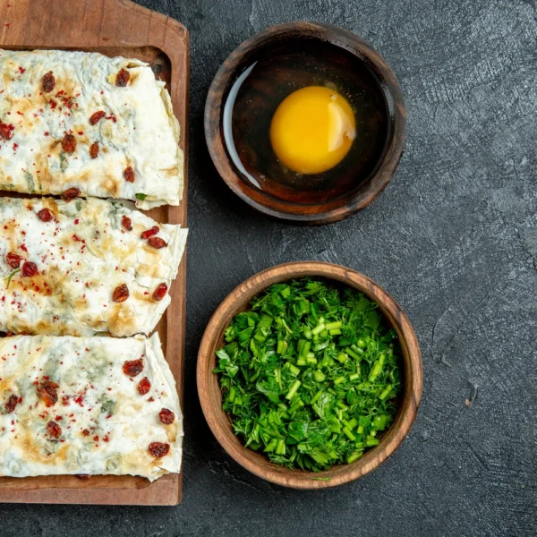 top-view-delicious-qutabs-rolled-green-filled-dough-slices-with-greens-dark-grey-space
